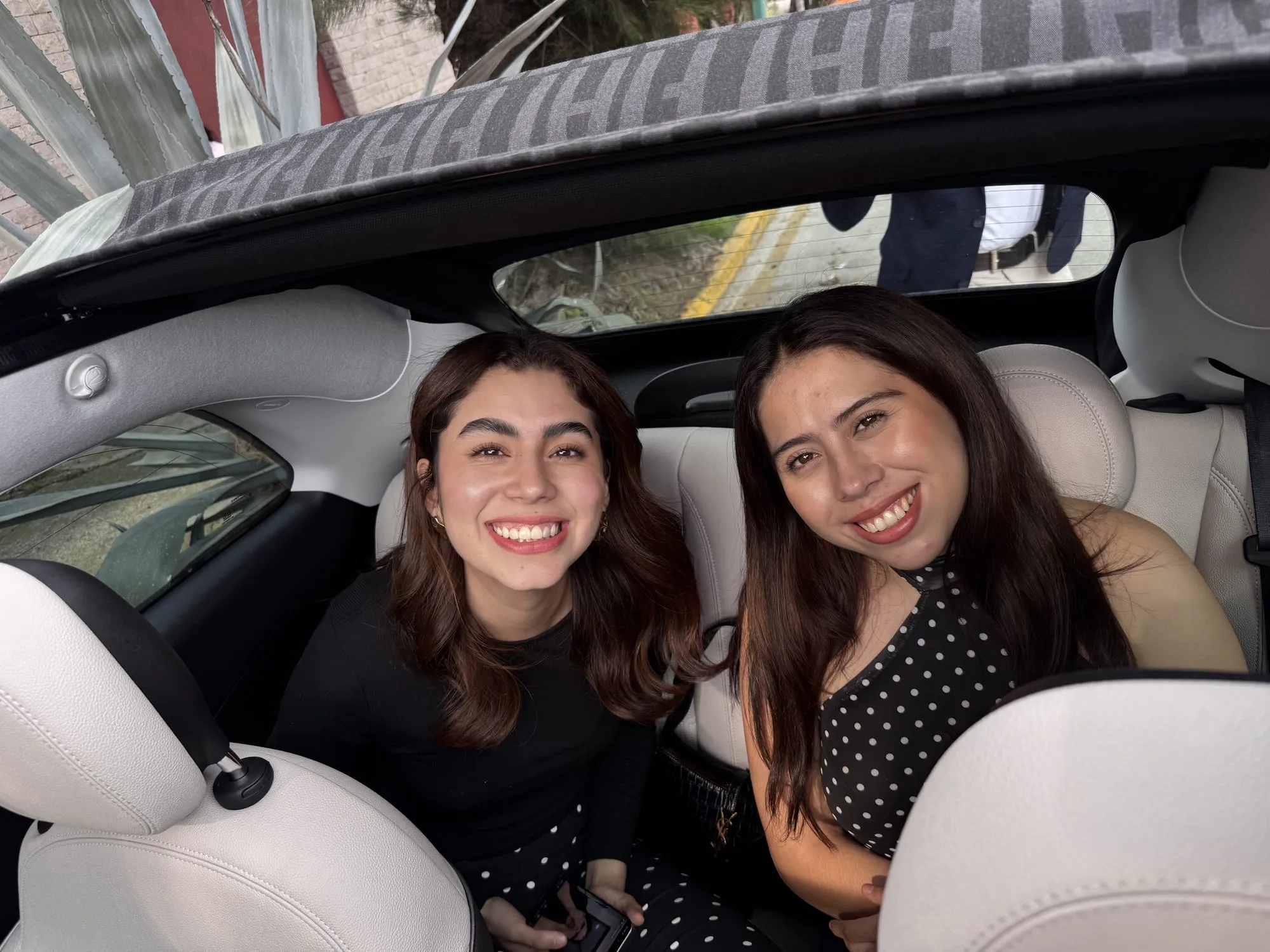 Dos pasajeras en los asientos traseros del Fiat 500e con la capota abierta